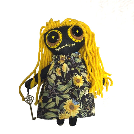 Hoodoo doll with yellow hair and floral dress on a white background