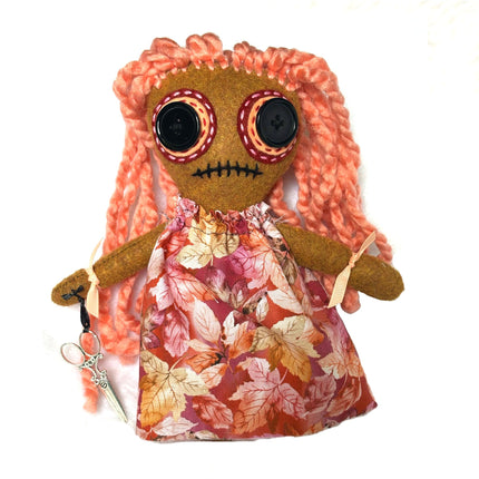 Hoodoo doll with pink hair and a floral dress on a white background