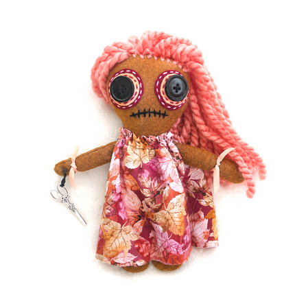Hoodoo doll with pink hair and a floral dress on a white background