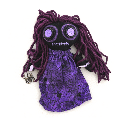 Hoodoo doll with purple hair and spiderweb dress on a white background