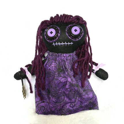 Hoodoo doll with purple hair and dress on a white background