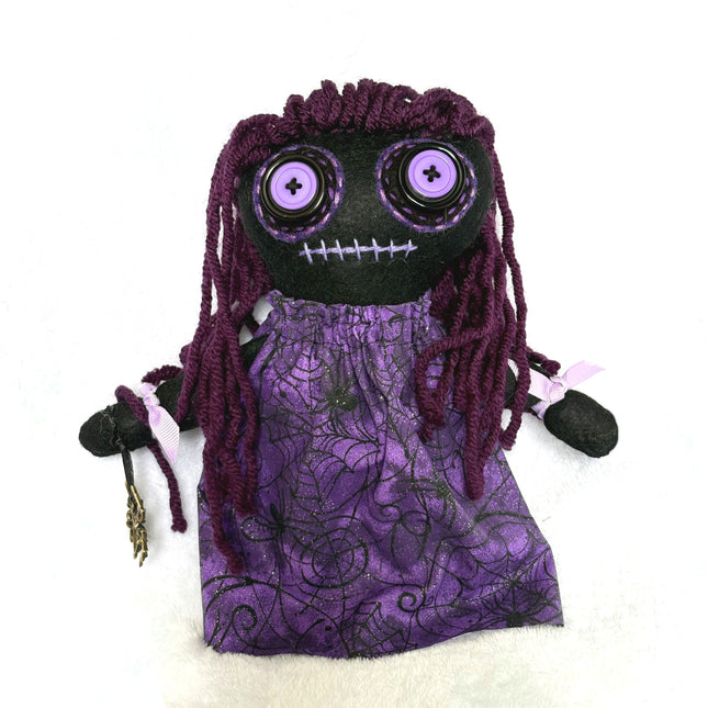 Hoodoo doll with purple hair and dress on a white background