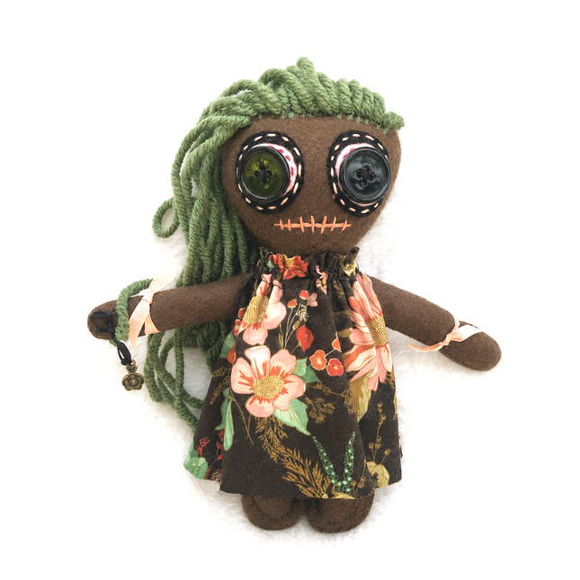 Stuffed Hoodoo doll with green hair and floral dress on a white background