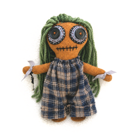 Earthy Hoodoo doll with green hair and plaid overalls on a white background