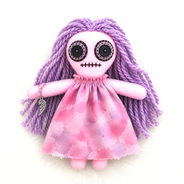 hoodoo protection doll baby with skeleton face and purple braided hair wearing a pink dress on a white background