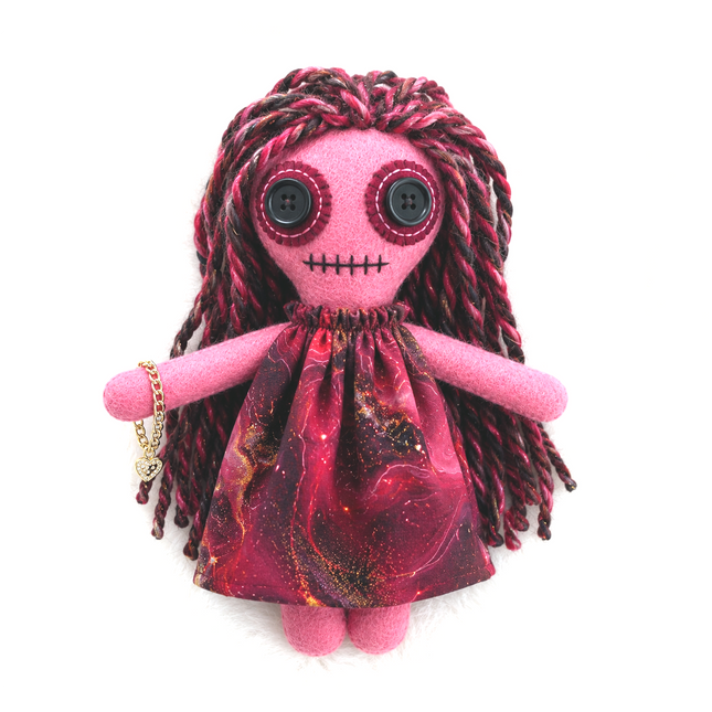 Pink hoodoo doll with red hair and black eyes on a white background
