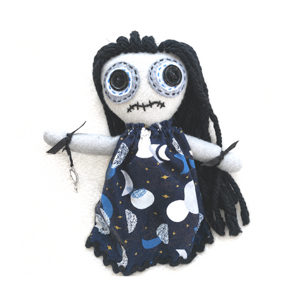 Plush hoodoo doll with black hair and blue eyes wearing a night sky patterned dress on a white background